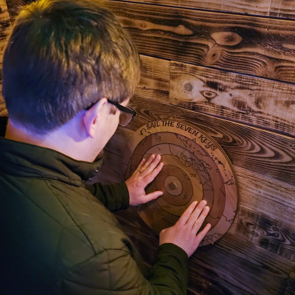 Tim with his hands on a wooden dial that appears to have a map on