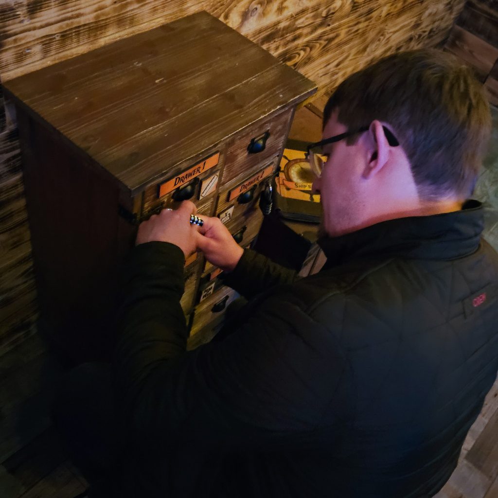 Tim kneeling down and fiddling with a padlock on a chest of drawers