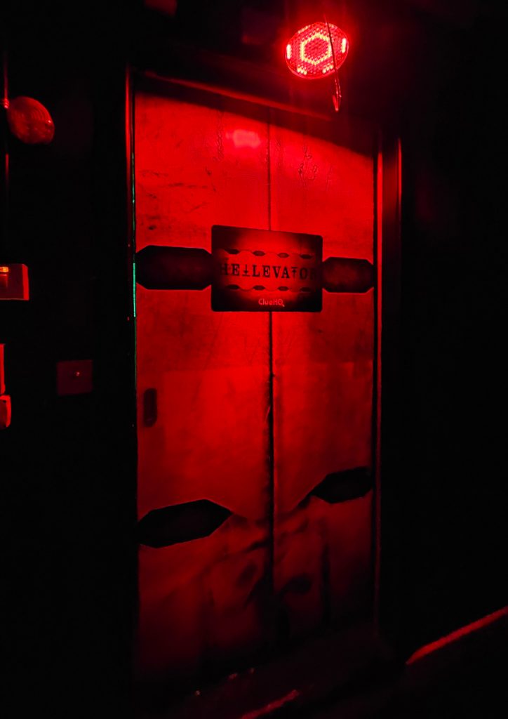 A lift door with Hellevator written on, bathed in red light