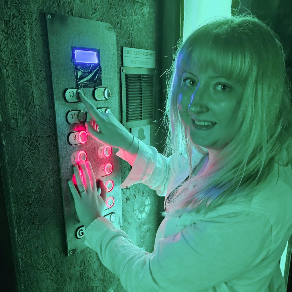 Becky smiling with her hand poised over 13 lift buttons