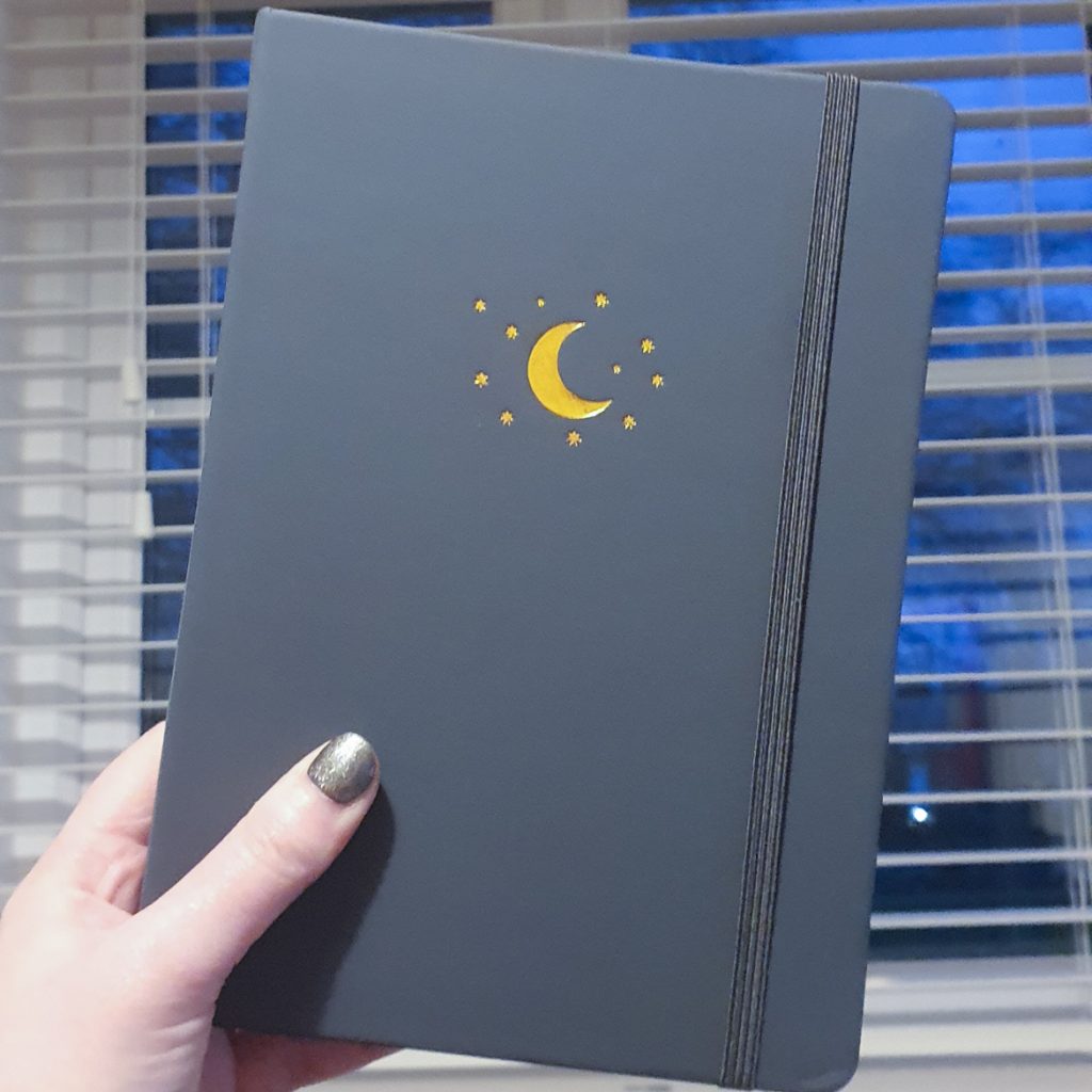 A bullet journal with a moon and stars on the cover