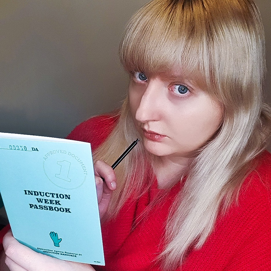 Becky, looking pensive, holding a blue booklet that reads "INDUCTION WEEK PASSBOOK"