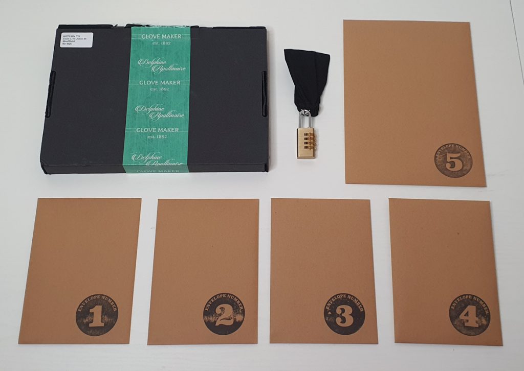 Flatlay of the black box, padlocked bag and five envelopes