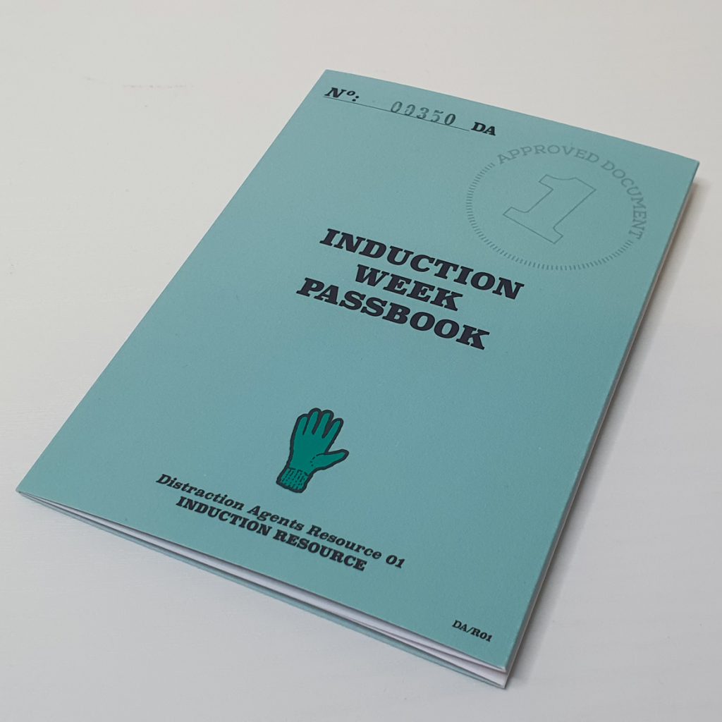 A blue booklet, reading "Induction Week Passbook"