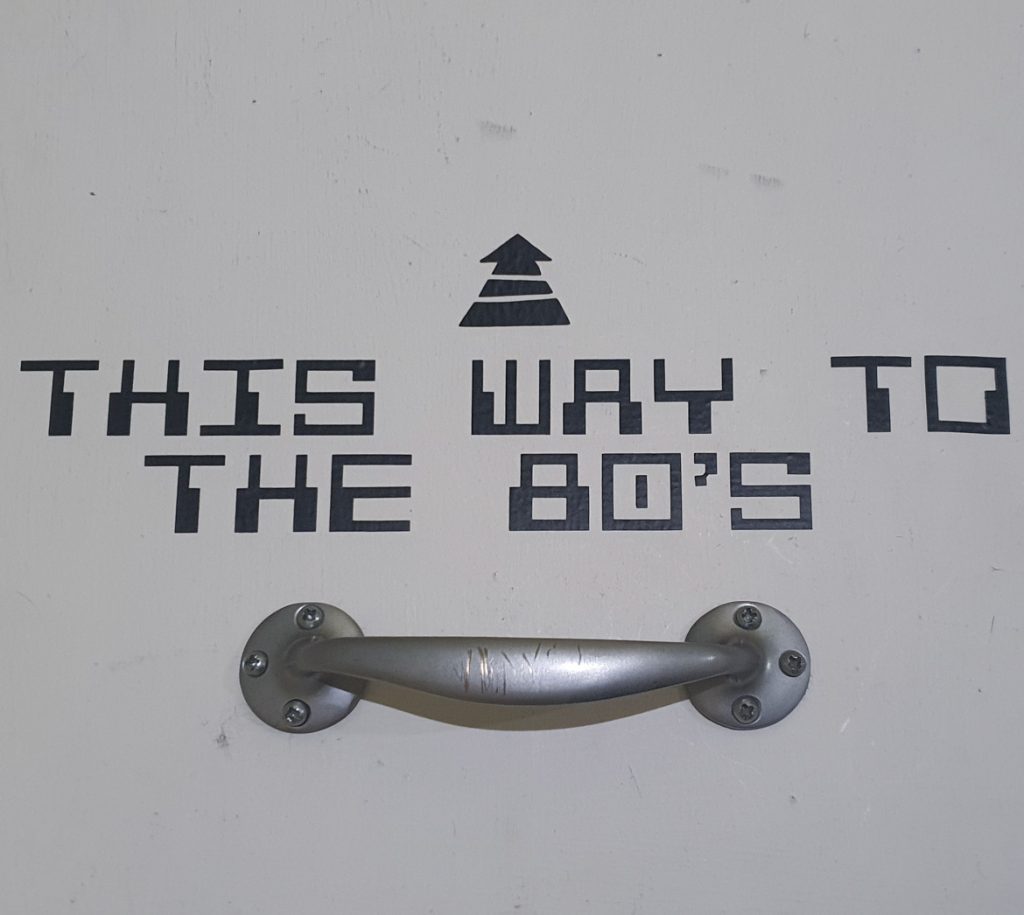 A sign reading "THIS WAY TO THE 80'S"