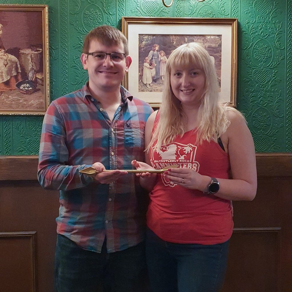 Becky and Tim holding a golden arrow in the success photo at Escapologic Escape Rooms