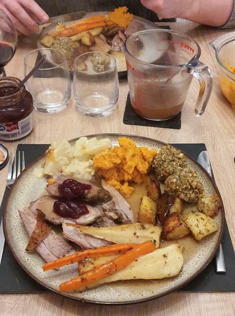 A plate full of turkey, potatoes, sweet potato mash, carrots, parsnips, stuffing and cauliflower cheese, covered in gravy