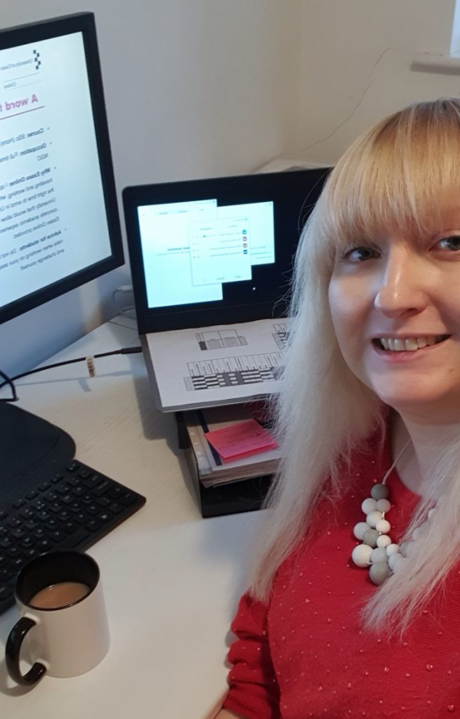 Becky smiling next to two computer screens