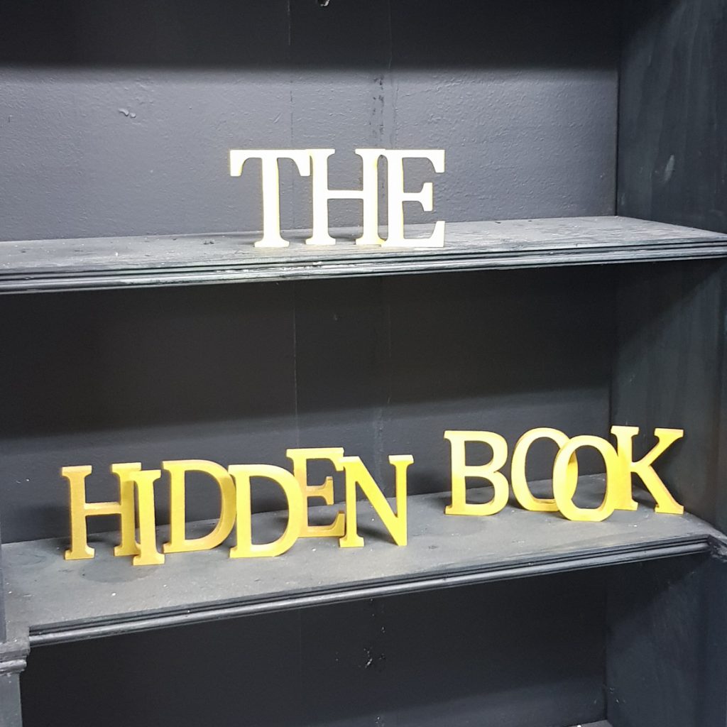 Letters spelling The Hidden Book on am empty shelf