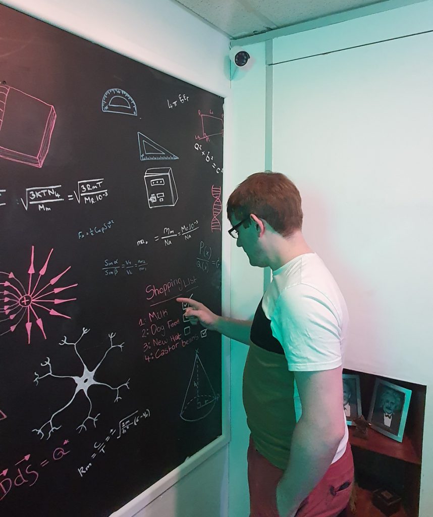 Tim pointing at a blackboard covered in science notation