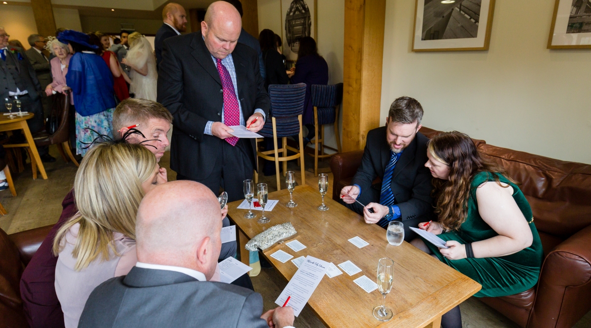 A group of guests looking at cards from "Mystery at the Wedding"