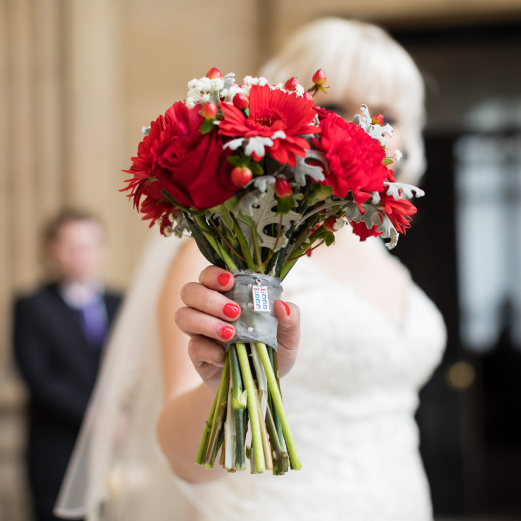 Becky holding out her bouquet towards camera, with a TARDIS charm hanging from it