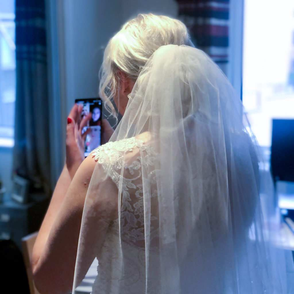 Becky facing away from camera wearing her wedding dress, on a video call with her Bride Control team