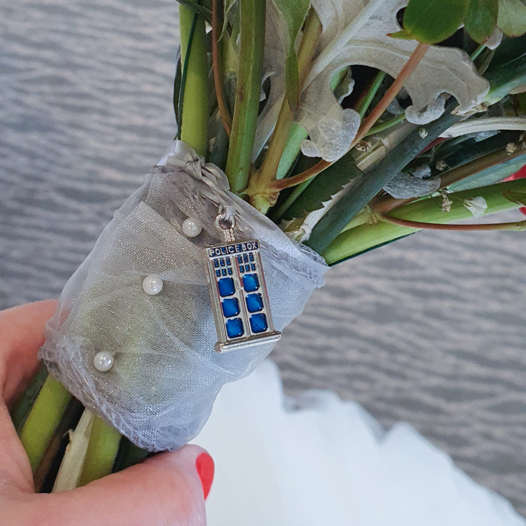 A TARDIS bouquet charm hanging from a bouquet